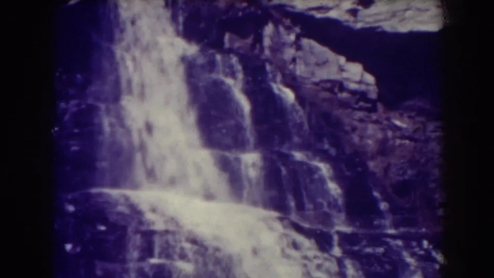 Blackwater Falls in West Virginia, shown as a bright cascade over rugged stone in purple-tinted 8mm footage from 1938.
