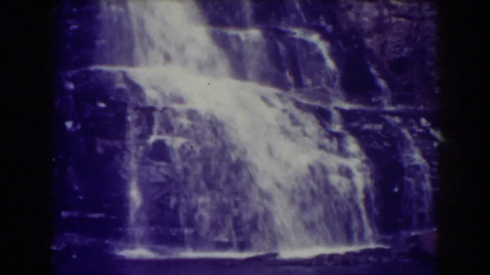 1938 8mm view of Blackwater Falls, with white water dropping over dark rock and a strong purple film cast.