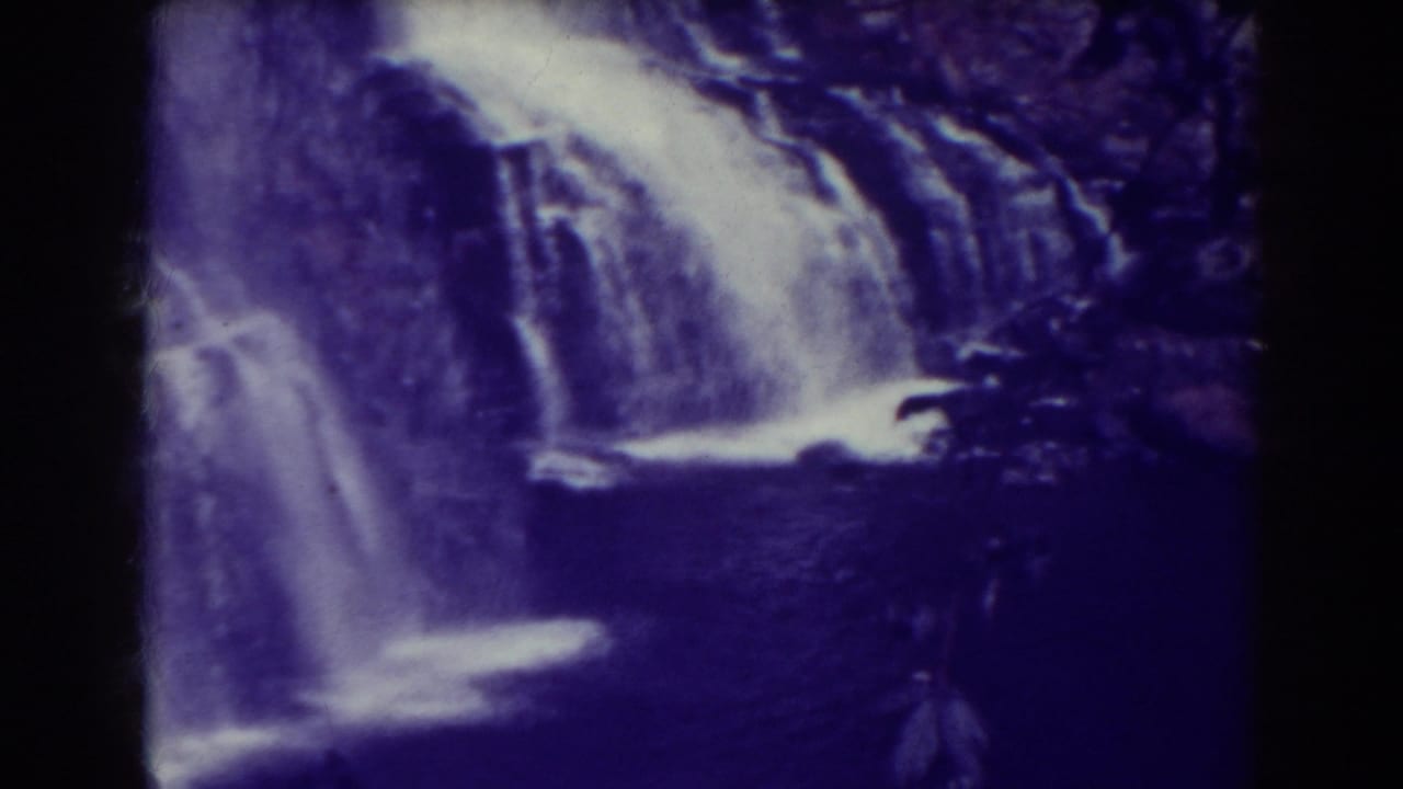 Waterfall cascading over rocks into a dark pool with black film borders.