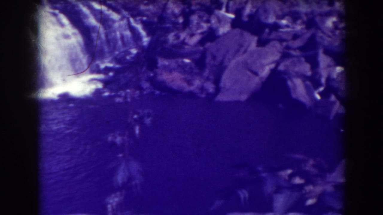Blackwater Falls appears in a 1938 8mm frame, with cascading water, large rocks, dark river surface, and purple film cast.