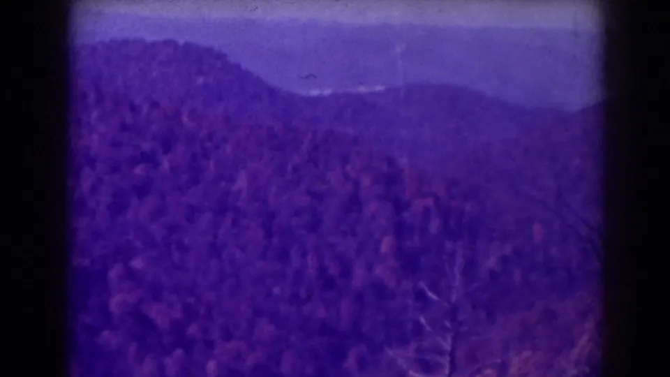A purple-shifted 8mm view of wooded hills near Blackwater Falls, with layered ridges and visible film-frame edges.