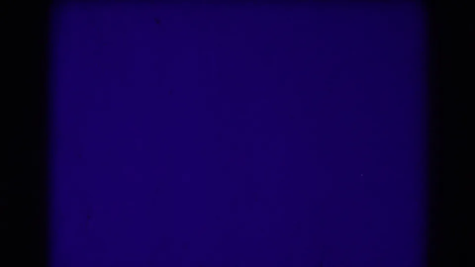 A heavily blue-purple 8mm frame where the landscape drops into near abstraction, leaving film texture and gate borders visible.