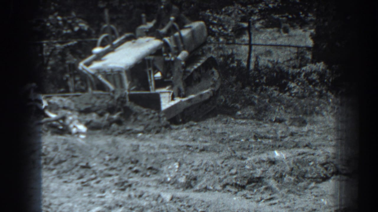 Tracked front-loader tractor working in a muddy construction area.