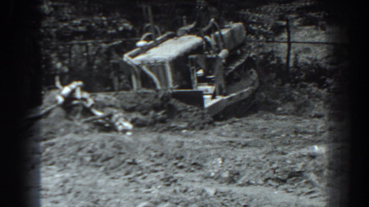 Front-loader tractor beside dirt and scattered material at a worksite.