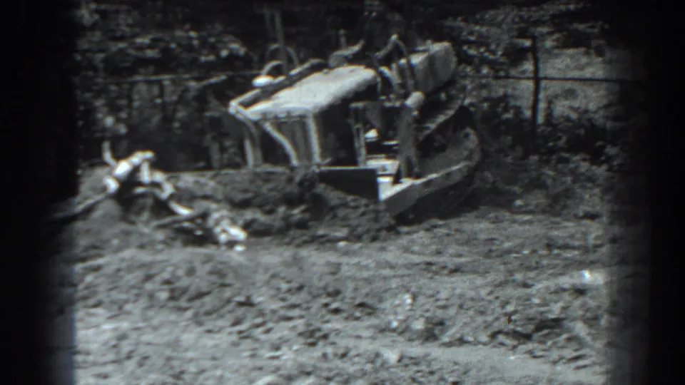 1938 Cumberland, Maryland frame with a tracked loader positioned near loose dirt and debris at an outdoor worksite.