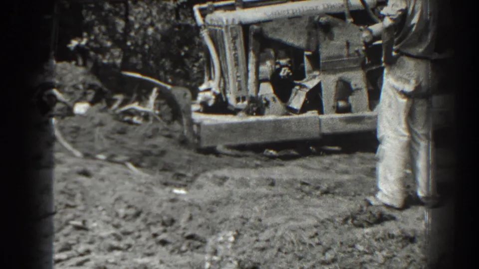 A bulldozer and blade remain in view as the man stands partly cropped in the 1938 Cumberland, Maryland footage.