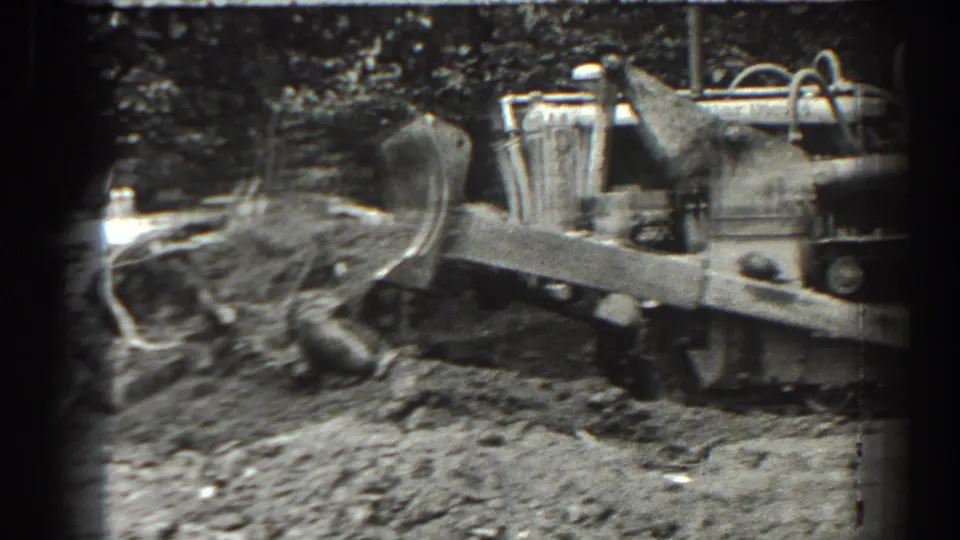 A close view shows the tractor's front implement near loose soil, with the tracked body cropped at the right edge.