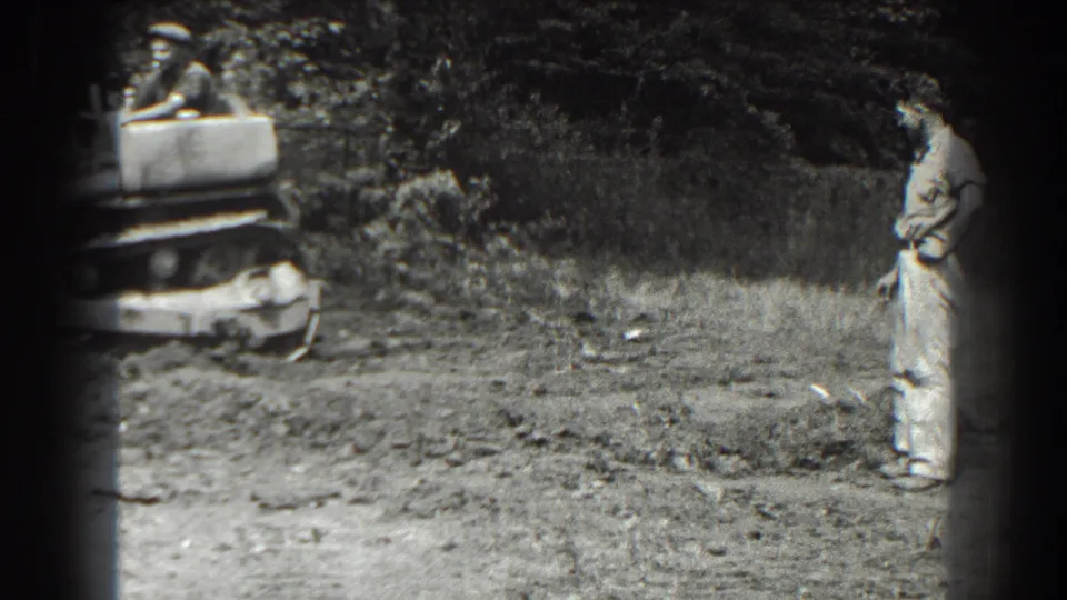 In Cumberland, Maryland, 1938, a man stands on rough ground while a small roadwork machine is partly visible at the left edge.
