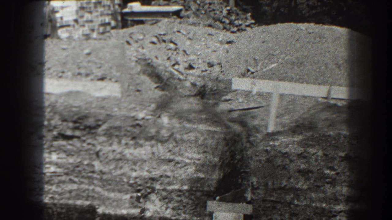 1938 Cumberland, Maryland 8mm frame showing dug earth, debris, and a low concrete or formwork edge at a construction site.