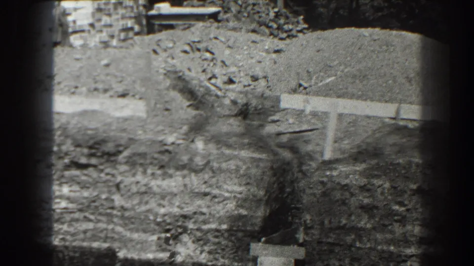 1938 Cumberland, Maryland 8mm frame showing dug earth, debris, and a low concrete or formwork edge at a construction site.