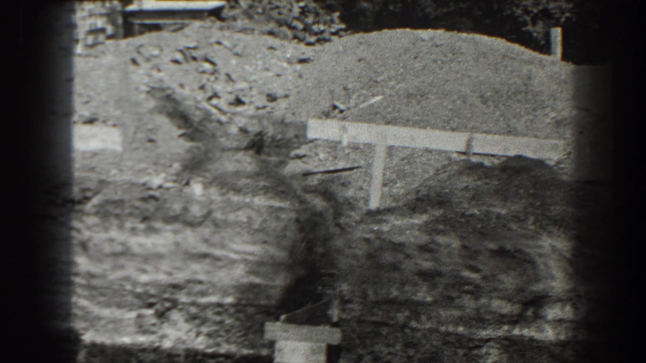 Construction excavation with mounded earth, rough debris, and a low horizontal form.