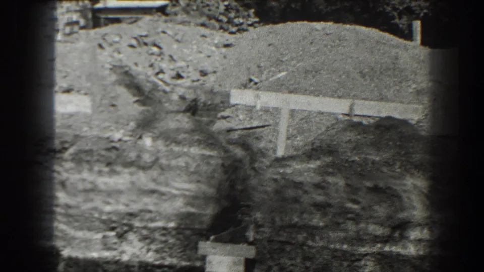 Black-and-white 8mm view of a Cumberland construction area with mounded earth, rough ground, and a low concrete or timber form.