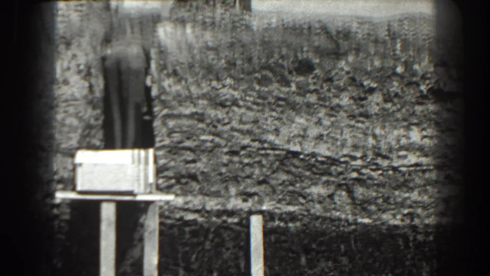1938 Cumberland, Maryland 8mm frame showing a man near a rough hillside excavation with a pale box or board on a stand.