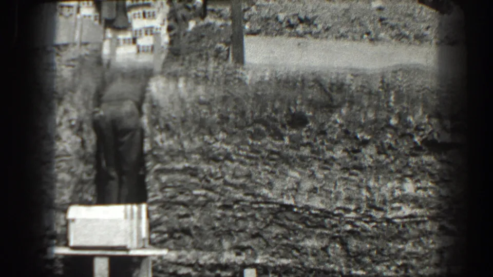 1938 Cumberland, Maryland frame with a man standing beside an exposed earthen hillside and a pale foreground stand.