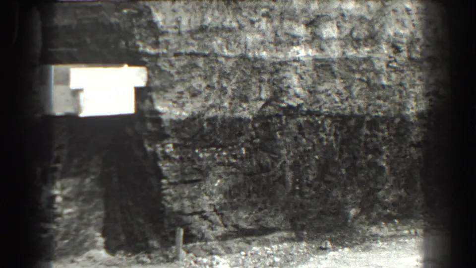 1938 Cumberland, Maryland 8mm frame showing a dim stone-lined underground passage with a bright light at left and scattered debris below.
