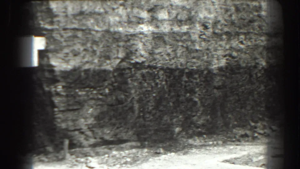 1938 Cumberland, Maryland frame with a rough stone wall, dim floor area, and the edge of a bright light source near the left side.