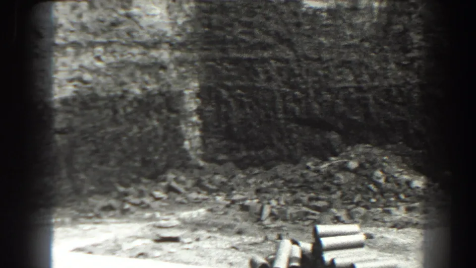 1938 Cumberland, Maryland frame showing a dim stone passage, scattered rubble, and several short pipe-like objects near the lower right edge.