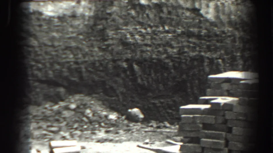 Cumberland, Maryland 1938 frame showing a cut earth bank, rubble, and a stack of bricks beside the excavation.