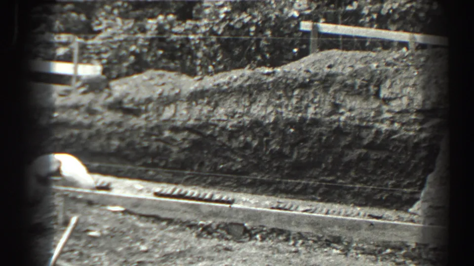 Cumberland, Maryland 1938 home-movie frame showing a worker near a street-edge excavation, with a dirt mound and long concrete form above.