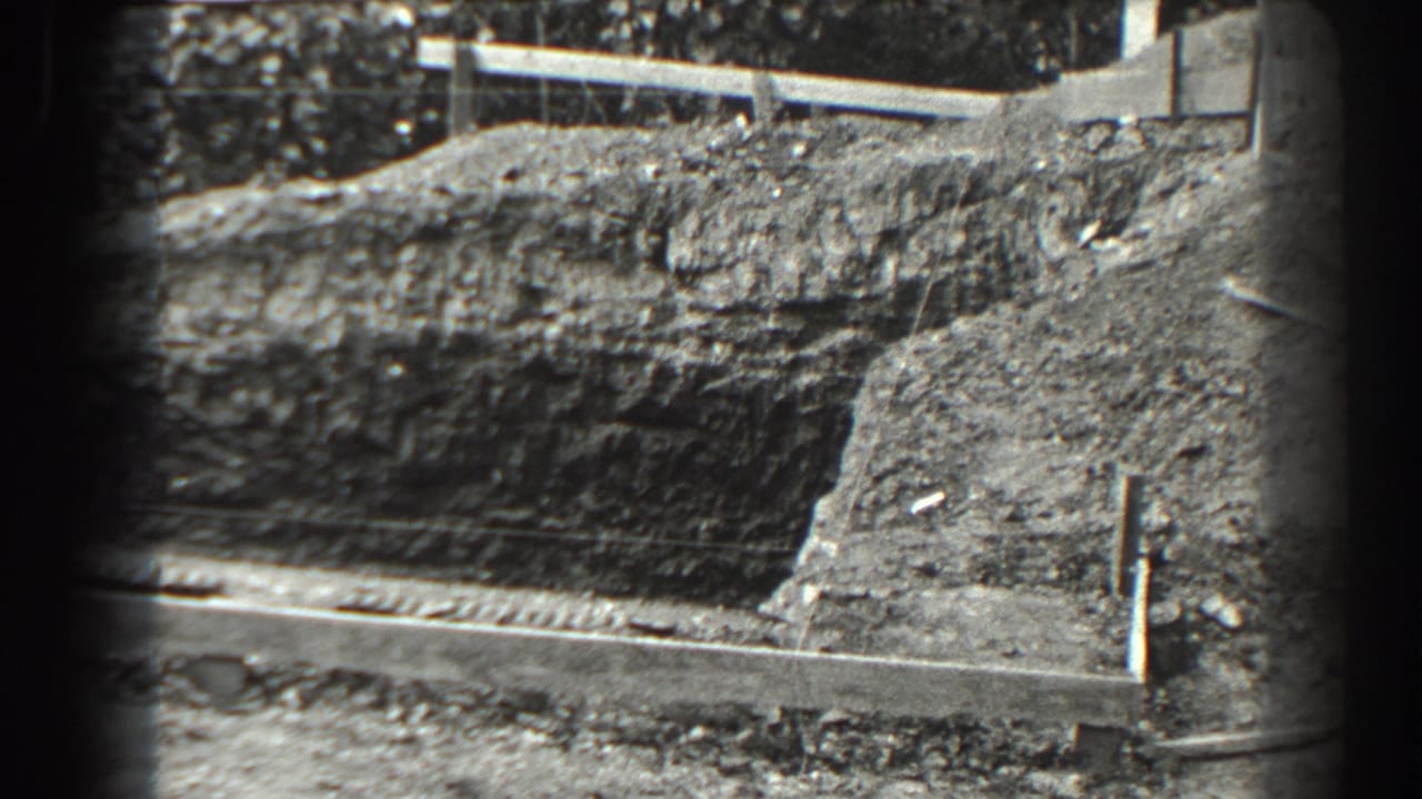 Excavated dirt bank with wooden edging and debris at a construction site.