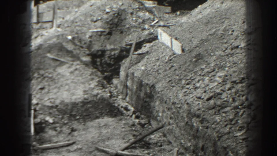 1938 Cumberland, Maryland home-movie frame showing a deep cut in the ground, plank formwork, dirt mounds, and construction debris.