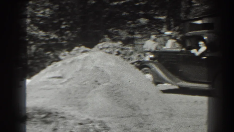 A dark 1930s car is parked beside the construction area in Cumberland, with at least one person visible near the vehicle.