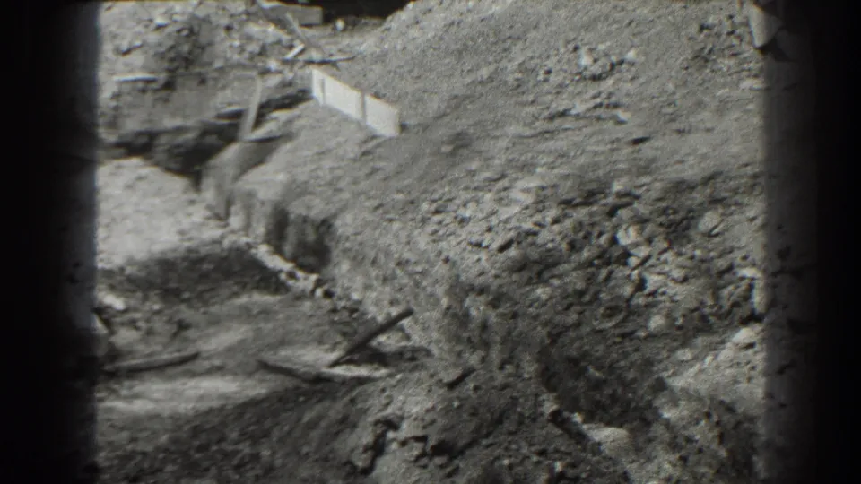 1938 Cumberland, Maryland home-movie frame showing rough excavation ground, dirt piles, and partial construction materials.