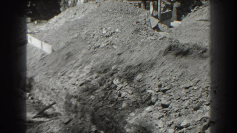A dirt pile and rough work area appear in this 1938 Cumberland construction-site view, with materials partly visible behind it.