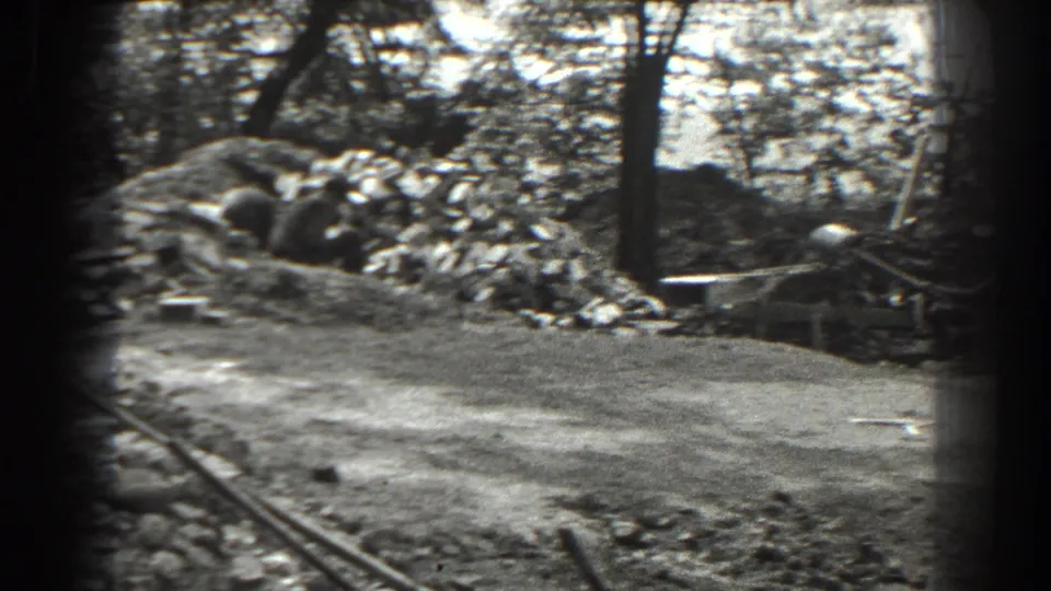 1938 Cumberland, Maryland frame showing a trench, excavated soil, trees, and a partly visible worker in the wooded work site.