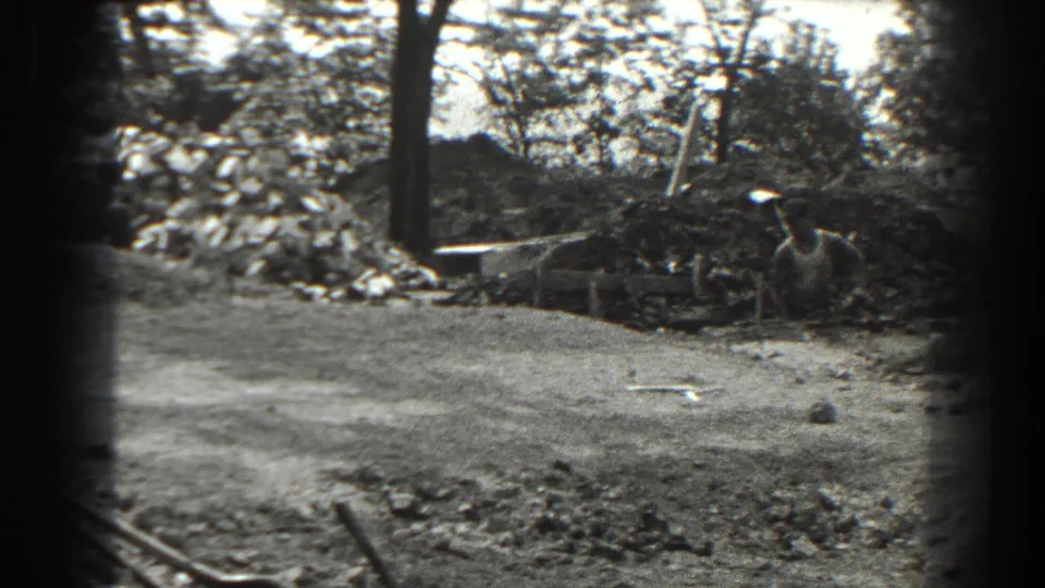 1938 Cumberland, Maryland footage frame showing men with shovels working near a trench in a tree-lined dirt clearing.