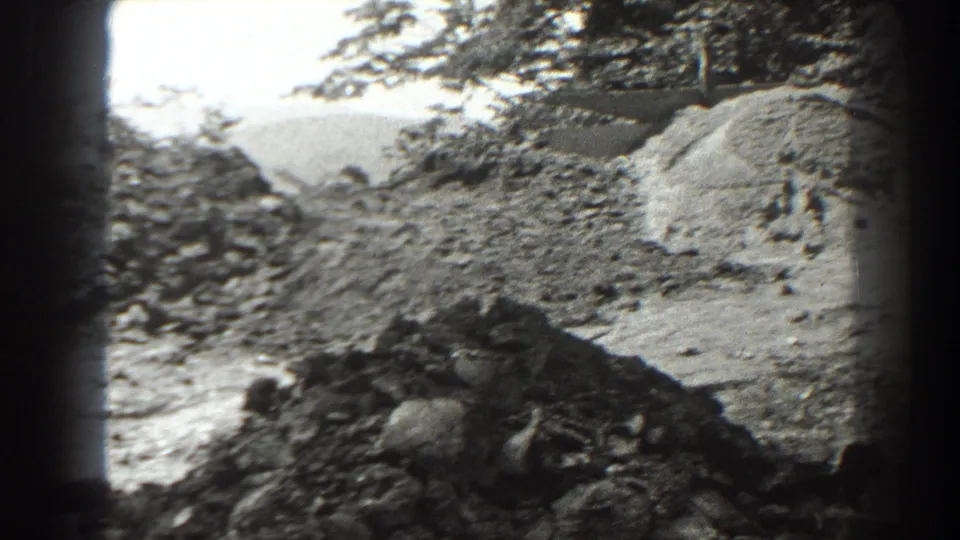 1938 Cumberland, Maryland work-area view with gravel or ore piles, trees, and rough ground seen through 8mm home-movie framing.