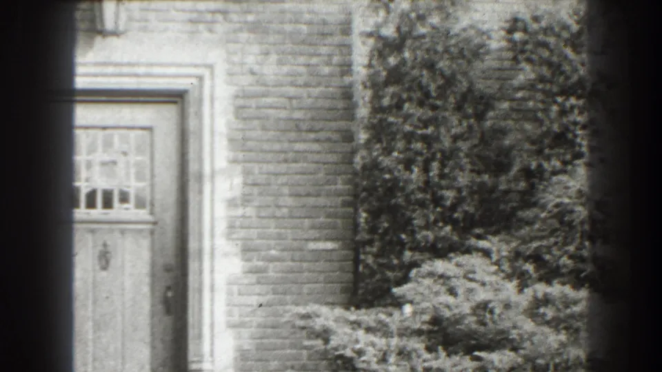 The frame centers on the house doorway and surrounding brickwork, with ivy and shrubs visible beside the entrance in Cumberland, Maryland footage.