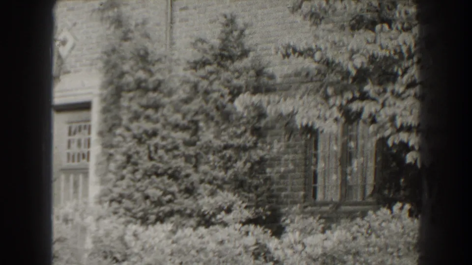 1938 Cumberland, Maryland frame with a brick house, multi-pane windows, and dense planting across the lower facade.
