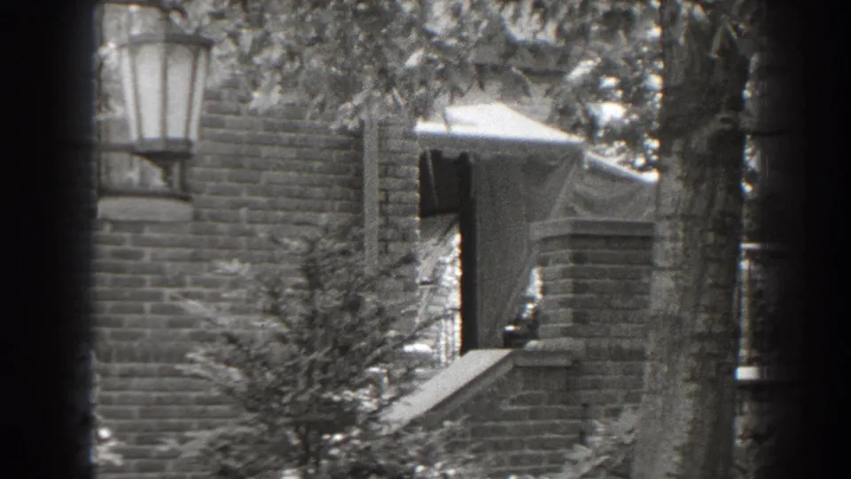 A second 1938 Cumberland frame holds on the brick house exterior, showing the awning, steps, wall lantern, and leafy branches.