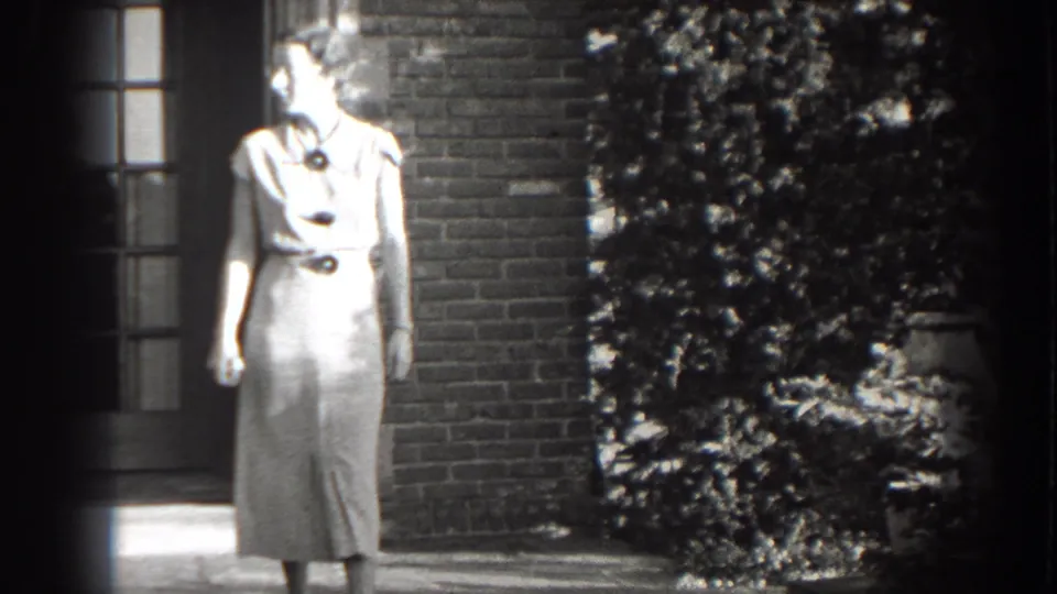 Adult woman in a light belted dress looks off to the side outside a brick building in Cumberland, Maryland.
