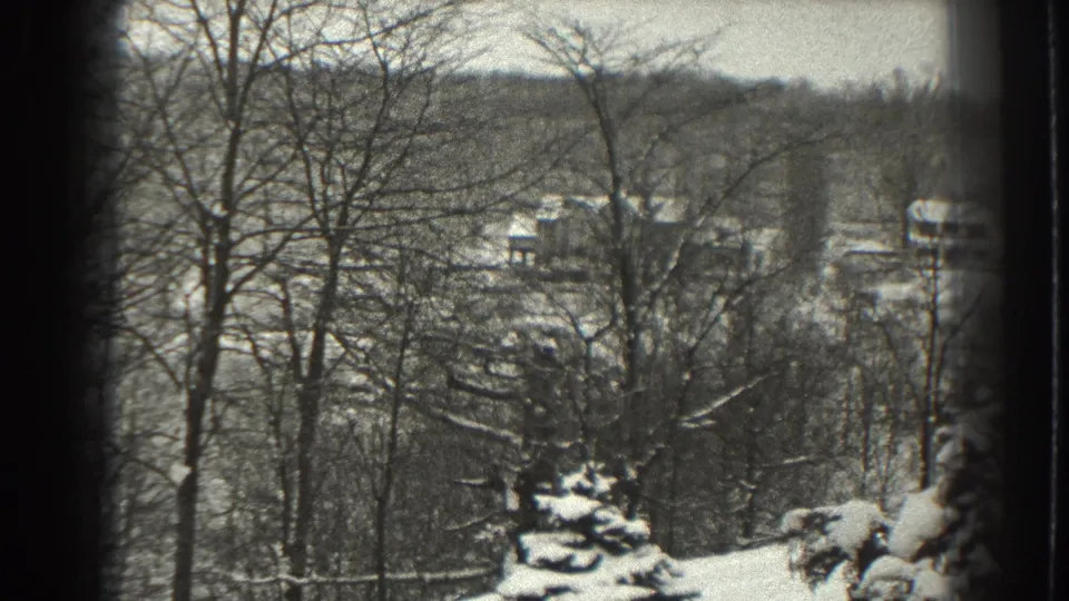 1938 Martinsburg, West Virginia home-movie frame showing snowy trees, evergreens, and distant farm buildings on a hillside.