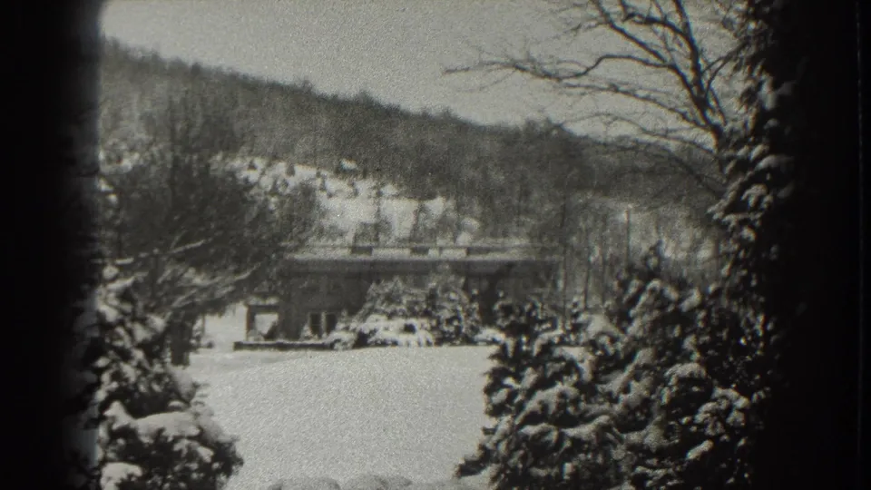 1938 Martinsburg, West Virginia home-movie frame showing snow-covered trees, a low bridge, distant houses, and a wooded hillside.
