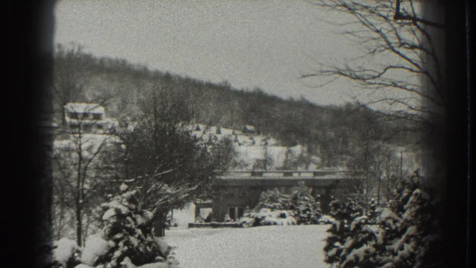 1938 Martinsburg, West Virginia winter view with snow-covered trees, a distant building, and wooded hills in black-and-white 8mm footage.