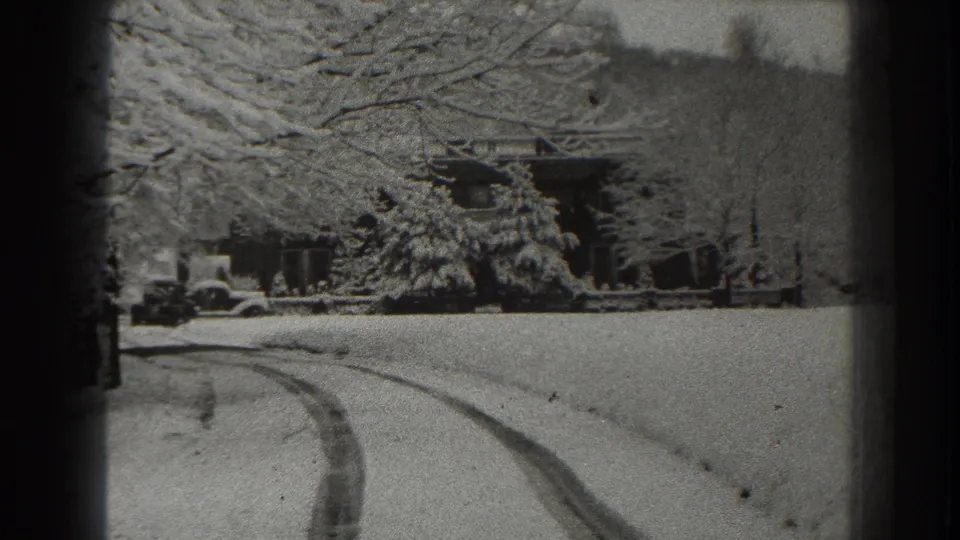 1938 Martinsburg, West Virginia home-movie frame showing tire tracks in snow leading toward a house, trees, and a parked automobile.