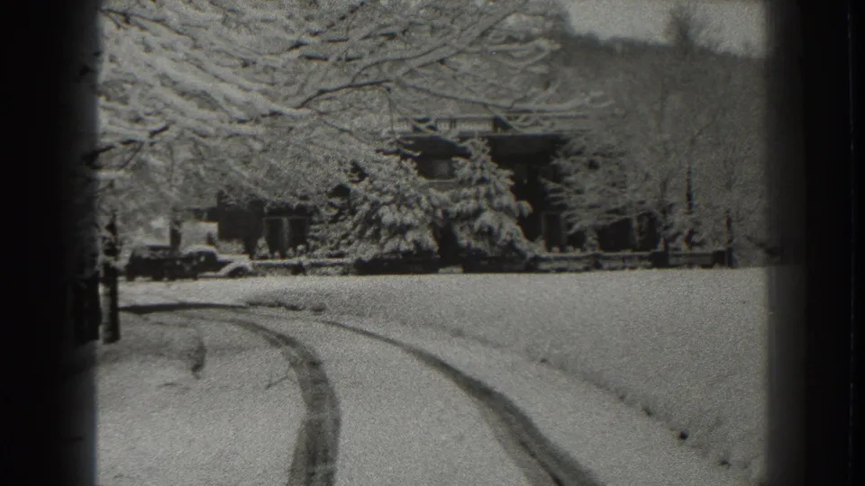 Late-1930s Martinsburg winter view showing snow-laden trees, a house in the background, tire tracks, and a parked automobile.