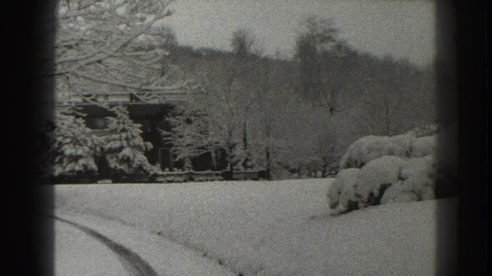 1938 Martinsburg winter view with a small cabin at left, snow-covered shrubs, bare trees, distant hillside, and tracks in the foreground.