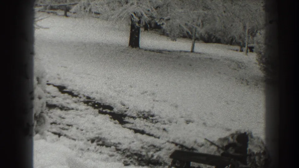 1938 Martinsburg winter home-movie frame showing snowy ground, bare trees, and a dark path or track through the foreground.