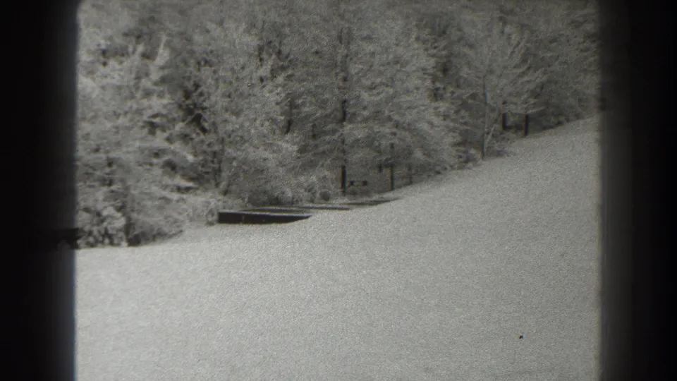 1938 8mm home-movie frame from Martinsburg, West Virginia, showing a snowy hillside and winter woods through dark framing edges.
