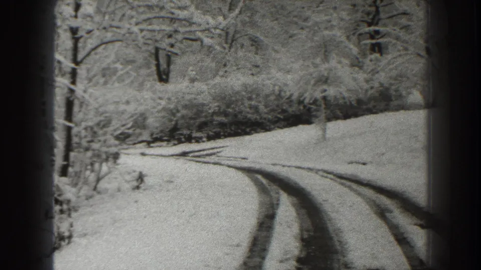 1938 Martinsburg-area winter road view with a snow-covered bend, visible tire tracks, and bare trees along the roadside.