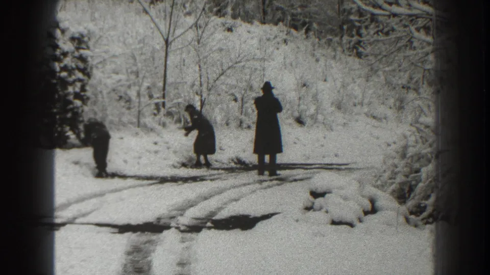Three people in winter coats stand or bend on a snowy road in Martinsburg, West Virginia, in 1938 home-movie footage.