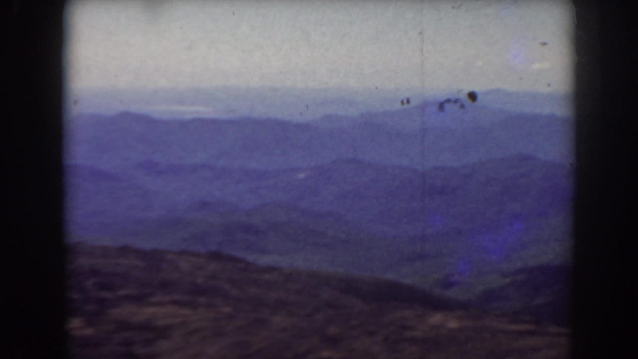 Layered mountain ridges under a pale sky with dark film gate edges.