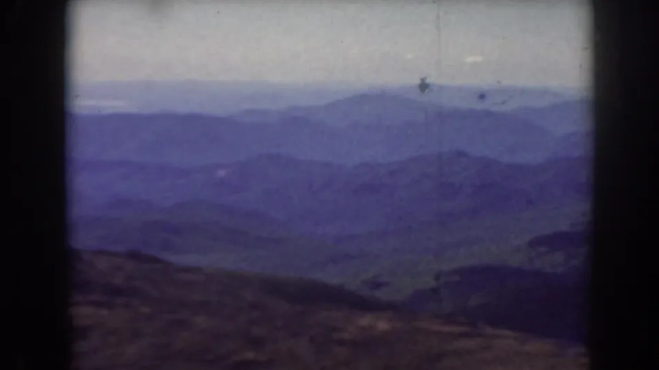 Mount Washington 8mm view with soft blue ridgelines, a hazy valley, and visible film specks across the pale sky.