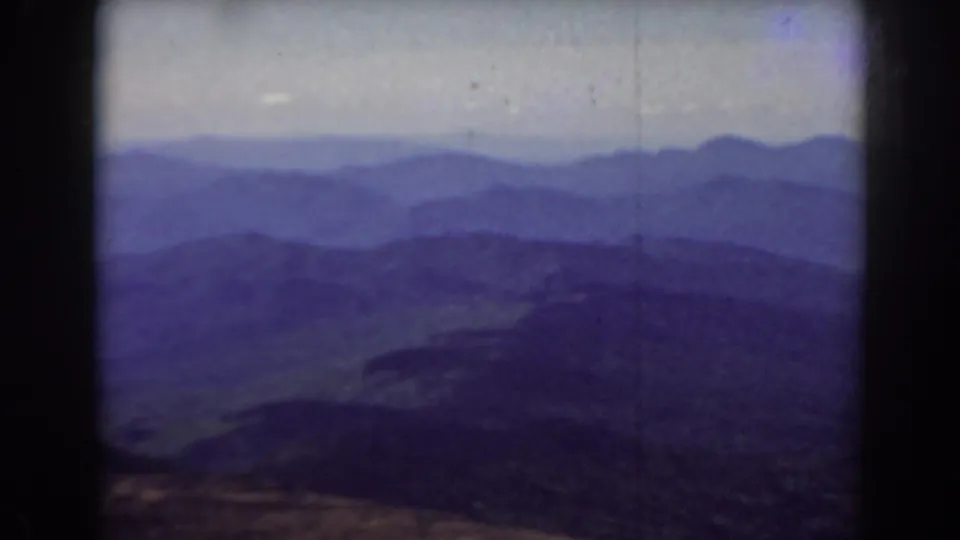 1938 Mount Washington landscape frame showing purple-blue ridges, a dark foreground valley shape, and soft early color film texture.