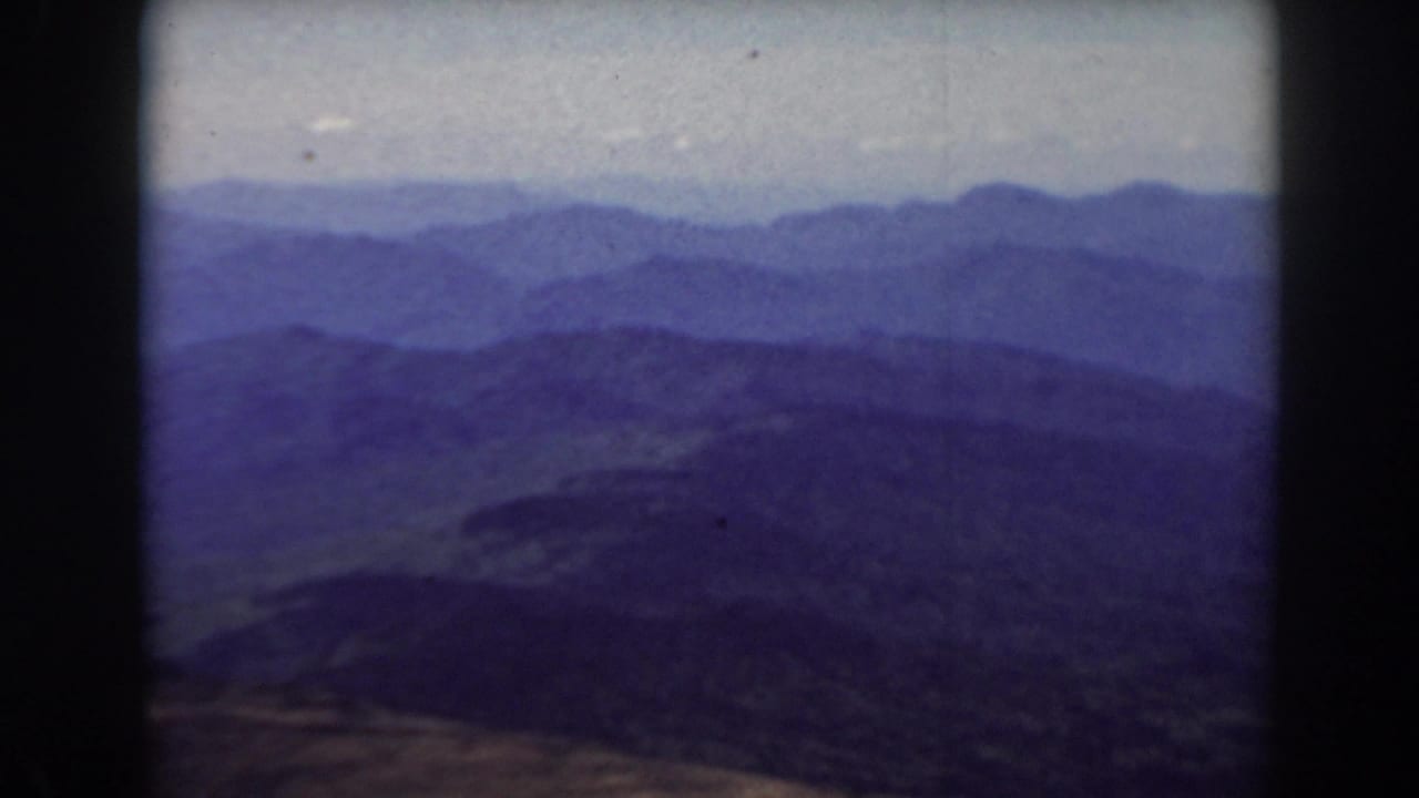 Layered mountain ridges under a hazy sky with dark 8mm frame borders.