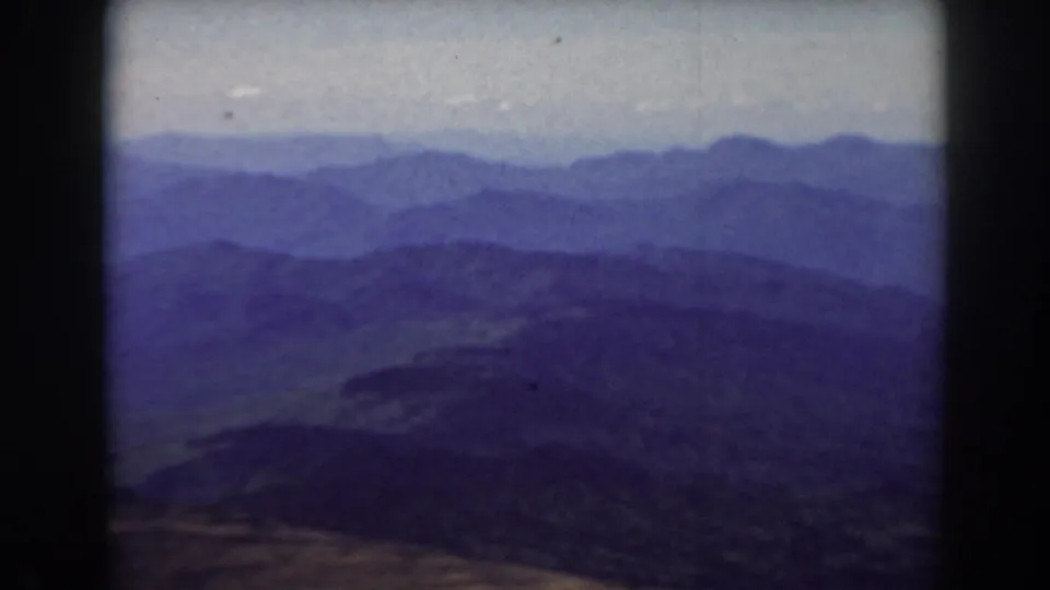 1938 Mount Washington home-movie frame showing distant blue-purple mountain ranges under a pale hazy sky.